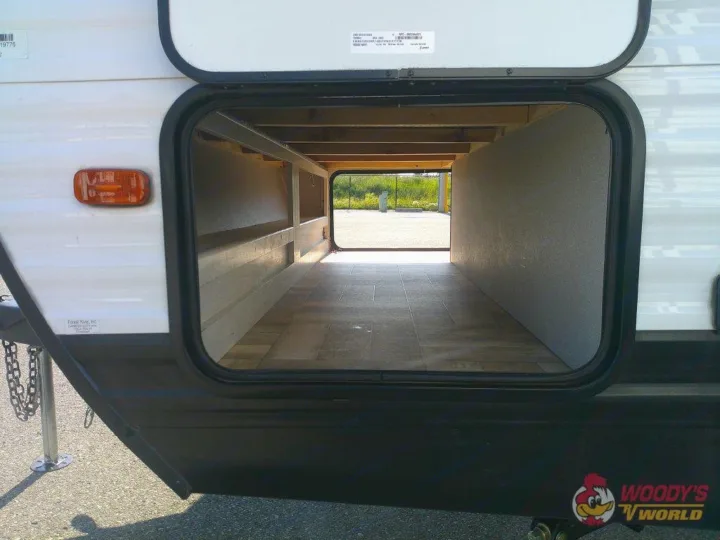 Spacious, empty pass-through storage compartment of an RV rental, open to reveal its depth and the view outside.. Forest River Shasta 2022