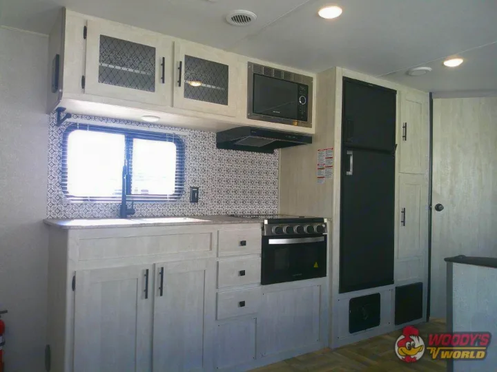 Explore this modern RV rental kitchen, featuring a full suite of appliances, sleek light cabinetry, and tiled backsplash.. Forest River Shasta 2022