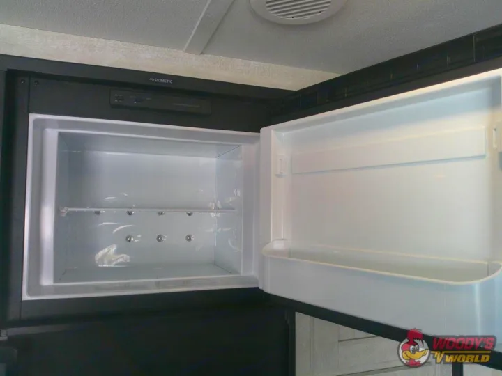 RV rental refrigerator interior: Open Dometic fridge with empty shelves and door compartments, ready for use.. Forest River Shasta 2022