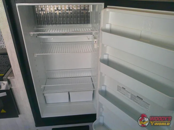 Open, empty RV refrigerator with shelves and door storage, ideal for an RV rental.. Forest River Shasta 2022