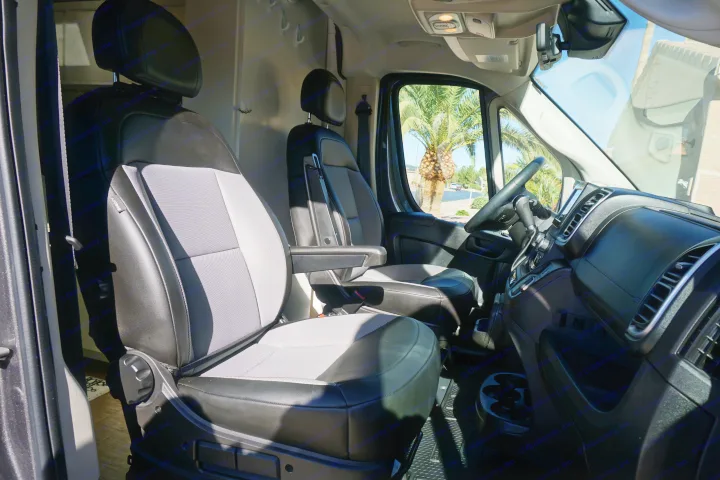 Spacious RV rental interior with driver & passenger seats, dashboard, and a sunny palm tree view.. Dodge Ram Promaster 2500 2022