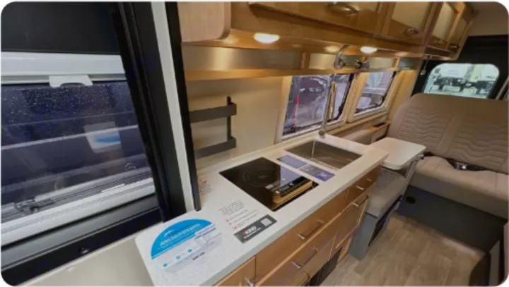 RV rental: Inside a camper van with a compact kitchen (sink, stove) and comfortable seating, ideal for your next adventure.. Coachman Nova 2024