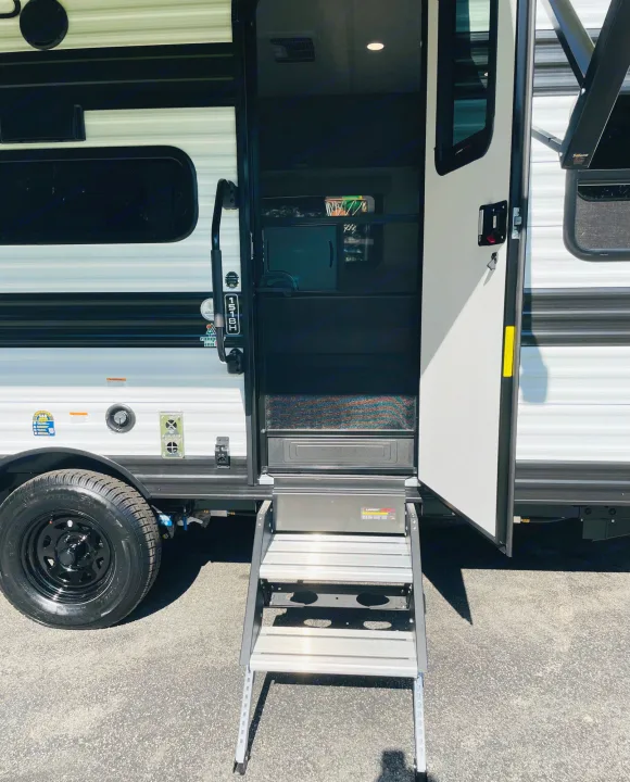 An RV rental, featuring an open door with extended, sturdy aluminum steps. Ready for your next road trip!. Grand Design Transcend One 151BH 2025