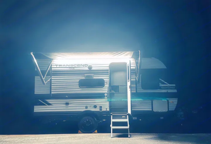 Night view of an RV rental: a Grand Design Transcend travel trailer with its lit awning extended and steps down, ready for adventure.. Grand Design Transcend One 151BH 2025