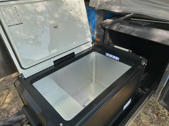 Open ICECO portable fridge/freezer, ideal for an RV rental. Shows empty interior and lid's food type temp guide.. Opus Camper Opus OP4 2024