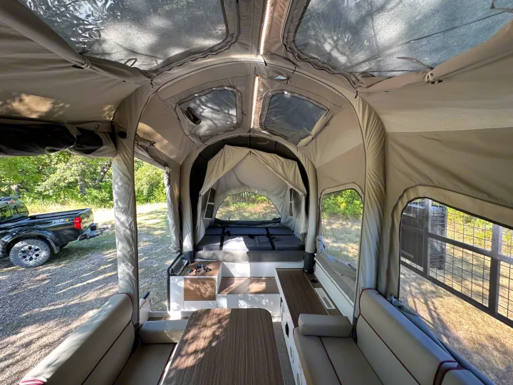 Inside a modern pop-up rv rental: bed, dining area, and panoramic windows.. Opus Camper Opus OP4 2024