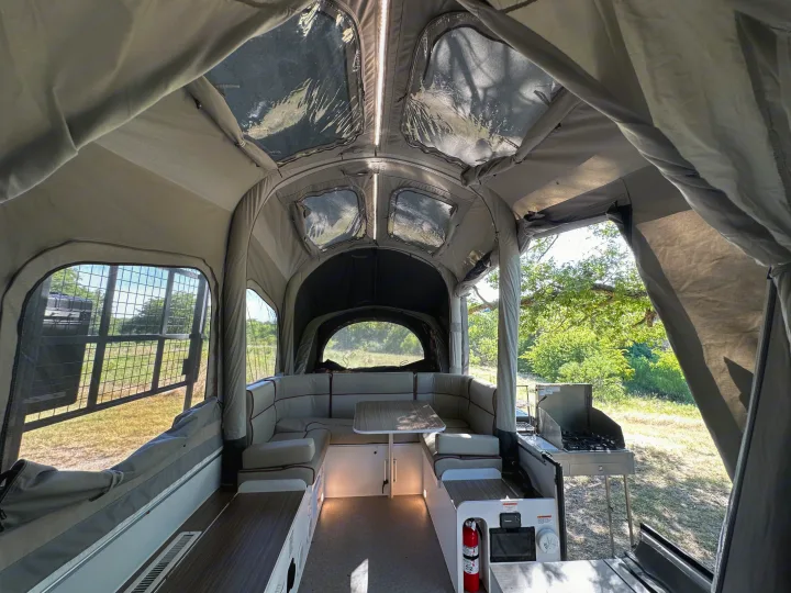 View inside a modern RV rental featuring a cozy dinette setup, clear ceiling windows & an outdoor kitchen.. Opus Camper Opus OP4 2024