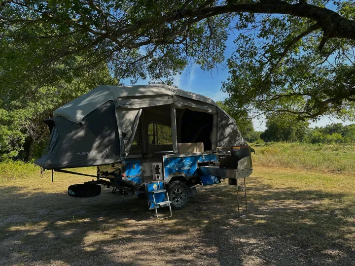 Opus off-road pop-up RV rental setup under trees for camping. Fully expanded, ready for outdoor adventures & cooking.. Opus Camper Opus OP4 2024