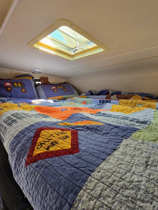Cozy RV rental bedroom with a colorful quilt, truck-themed pillows, and a skylight providing natural light.. Forester Forester Motorhome 2019