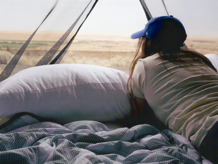 Cozy RV rental stay: a traveler rests on soft bedding, enjoying the desert landscape through a screened window.. Other Other 2022