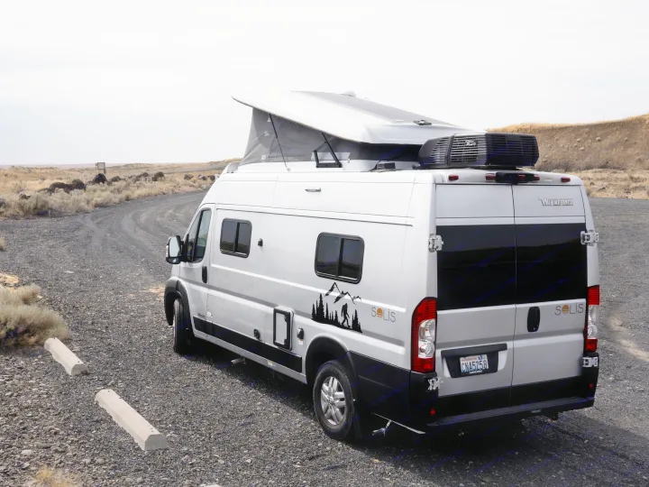 Silver Winnebago Solis RV rental with pop-top roof, parked on a gravel road.. Other Other 2022
