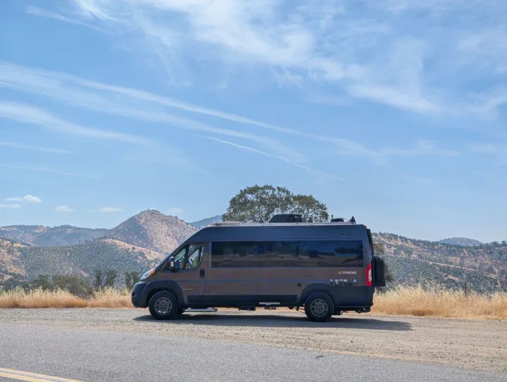 Thor Ethos camper van parked on a scenic mountain road. This dark grey RV rental is ready for adventure!. Entegra Coach Ethos 2023