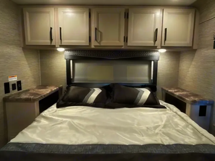 This RV rental features a comfortable bedroom with overhead storage, bedside tables, and a large bed, perfect for your next trip.. Thor Four Winds 2022