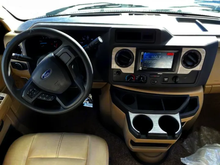 Interior of an RV rental: driver's view with Ford steering wheel, infotainment screen, and ample cup holders.. Thor Four Winds 2022