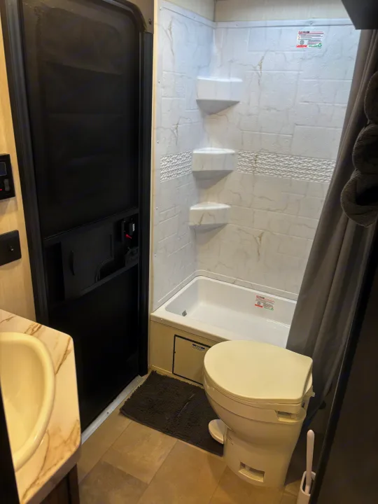 RV rental bathroom: compact interior with shower/tub, toilet, and sink. Enjoy comfort on the road.. Forest River Cherokee 26DBH 2024