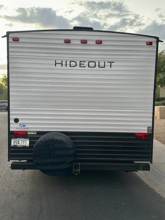 Rear of a "Hideout" travel trailer with a spare tire and Arizona license plate. This RV is available as an rv rental.. Keystone RV Hideout 2021