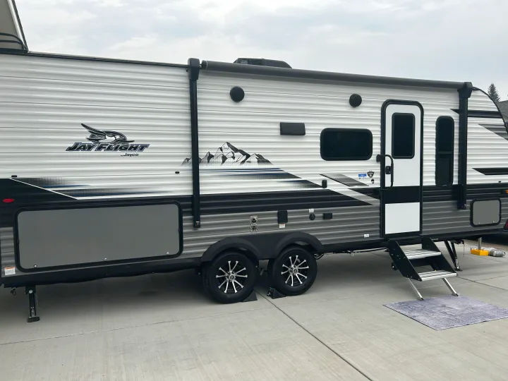 Side view of a new Jayco Jay Flight rv rental, a travel trailer with extended steps and an awning, ready for adventures.. Jayco Jay Flight 2024