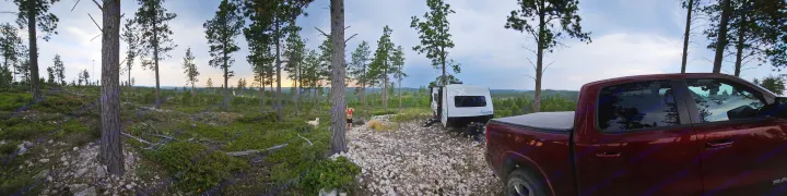 An RV rental and red truck parked at a rustic forest campsite. A person and light-colored dog play nearby.. Forest River Ibex 19MBH 2024