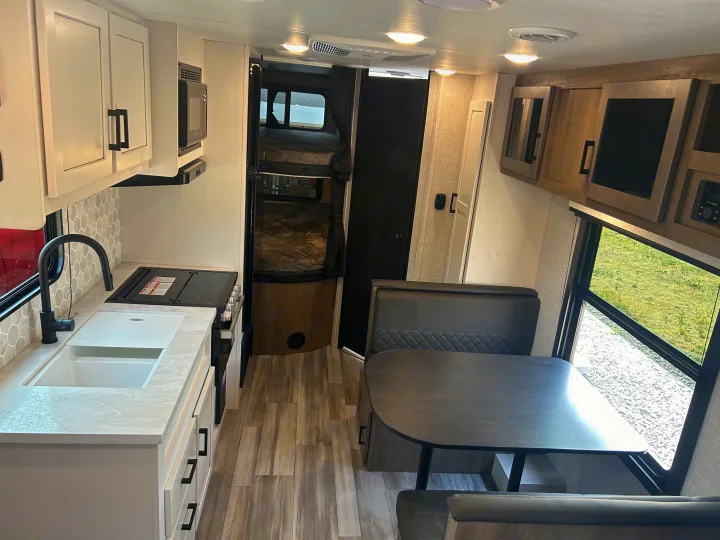 Spacious RV rental interior featuring a modern kitchen, dining booth, and bunk beds, perfect for travel.. Jayco Jay Flight 2024
