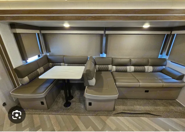 Comfortable RV rental interior featuring a U-shaped dinette with table and extended sofa seating.. Forest River Wildwood 2022