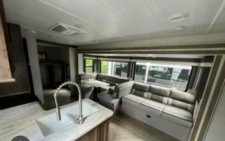 Spacious RV rental living area featuring U-shaped dinette, kitchen, and ample windows for bright views.. Forest River Wildwood 2022