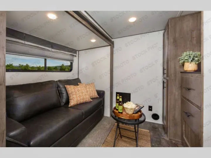 Spacious RV rental living area featuring a comfortable sofa, large window with views, and practical storage. Ideal for road trips.. Forest River Sabre 2021