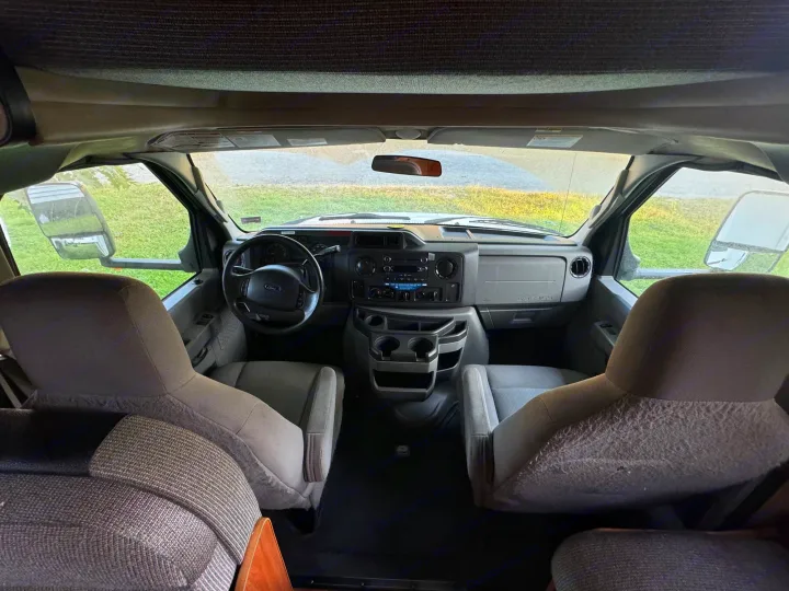 RV rental interior: The spacious front cabin with dashboard, steering wheel, and two front seats, as seen from the rear.. Thor Majestic 2017