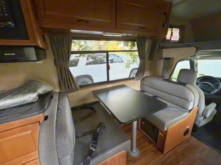 Spacious RV rental interior featuring a dinette with a black table and comfortable seating, plus a view of a parked SUV.. Thor Majestic 2017