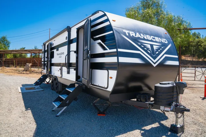 Modern black and white Transcend XPLOR RV travel trailer parked on gravel, ideal for RV rental adventures.. Grand Design Transcend Xplor 2024