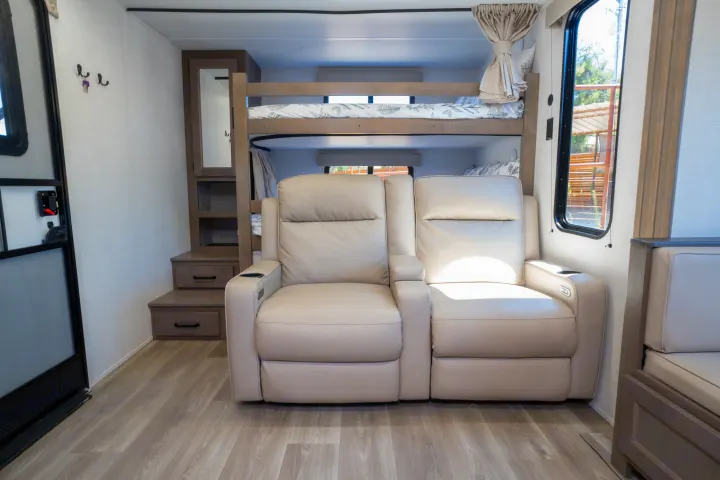 Light-filled RV rental interior featuring plush recliners, sturdy bunk beds, and modern storage steps.. Grand Design Transcend Xplor 2024