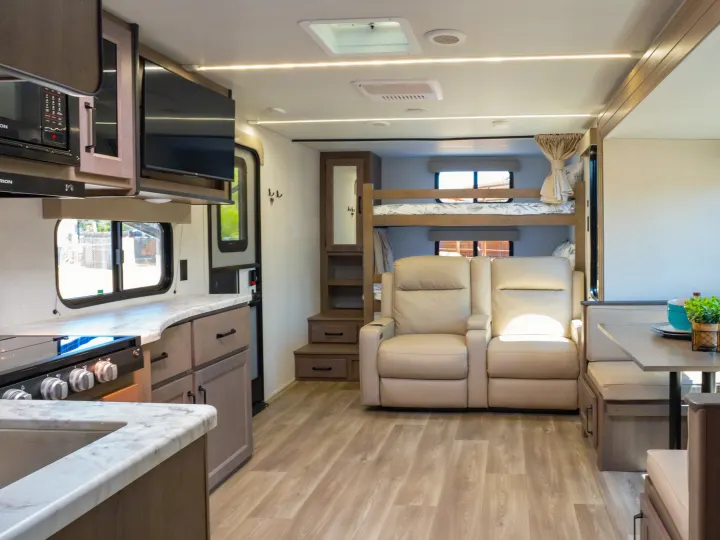 Spacious RV rental interior with kitchen, recliners, bunks, and dining. Ideal for family adventures.. Grand Design Transcend Xplor 2024