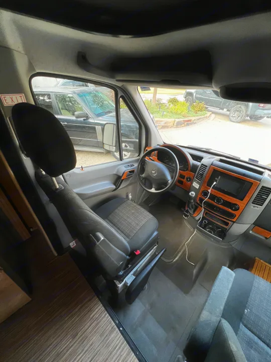 RV rental interior: Driver's seat, dashboard with wood trim, and view outside a Mercedes Sprinter van.. Forest River Coachmen Prism 2016