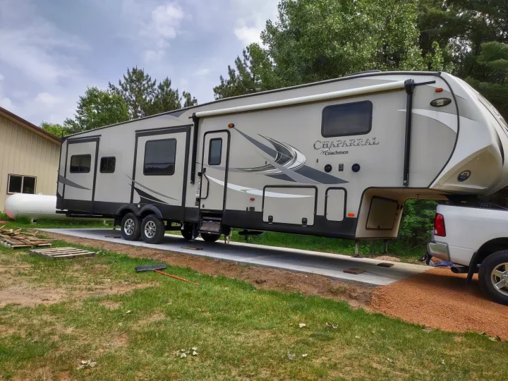 Fifth-wheel RV rental parked on a concrete pad, hitched to a white pickup truck, ready for a trip.. Forest River Coachmen Chaparral 2018