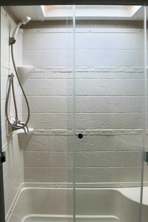 Compact shower and tub with textured walls and handheld showerhead, common in an RV rental for your adventures.. Forest River Coachmen Chaparral 2018