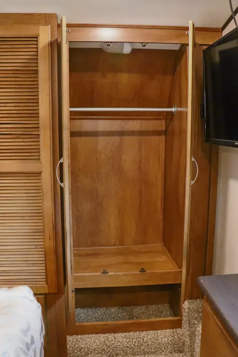 An open wooden wardrobe inside an RV rental, featuring a hanging rod, shelf, and lower storage space.. Forest River Coachmen Chaparral 2018