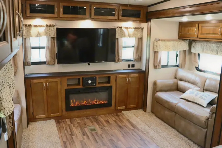 This inviting RV rental living area features a wall-mounted TV, electric fireplace, and a comfortable sofa with cabinets.. Forest River Coachmen Chaparral 2018