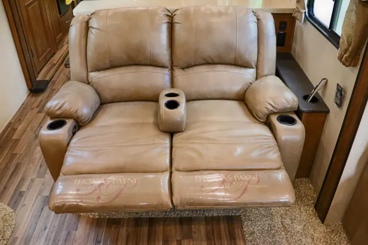 This RV rental offers a comfortable beige leather reclining loveseat with cup holders, perfect for relaxing inside.. Forest River Coachmen Chaparral 2018