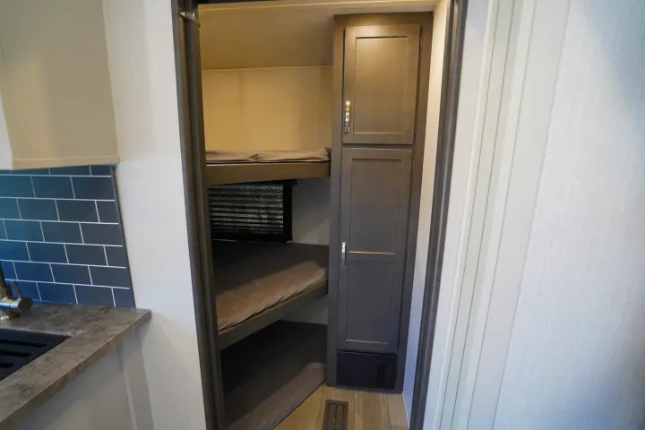 Step inside this RV rental showcasing bunk beds, a compact kitchen, and built-in storage solutions.. Keystone Cougar 2024