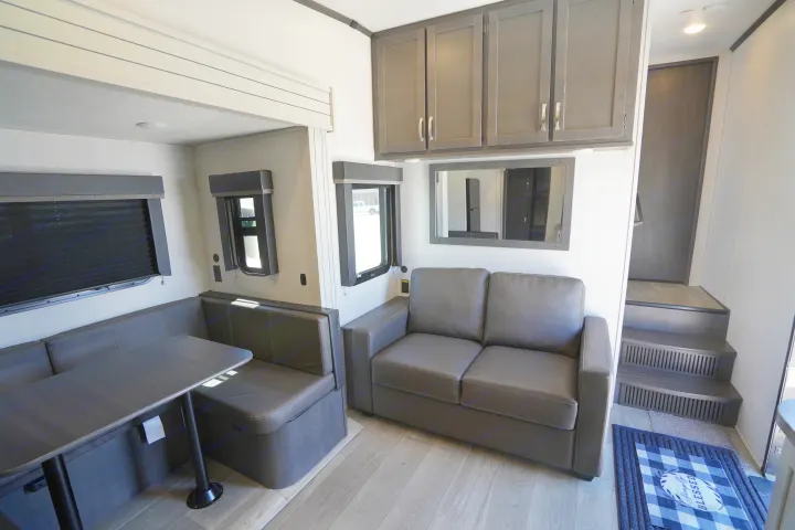 Spacious RV rental interior featuring a dinette, sofa, overhead storage, and steps to an upper level.. Keystone Cougar 2024