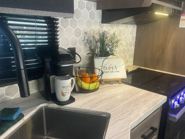 Inviting RV rental kitchen featuring a sink, Keurig, fruit basket, and stove, providing home comforts for your travels.. Highland Ridge RV Olympia 2022