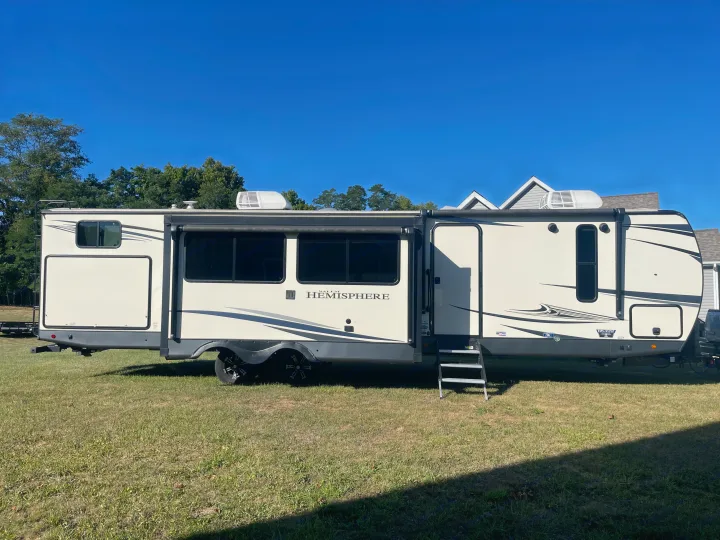 A long, cream-colored Forest River Hemisphere travel trailer, available for rv rental, is parked on green grass.. Forest River Salem Hemisphere 2020