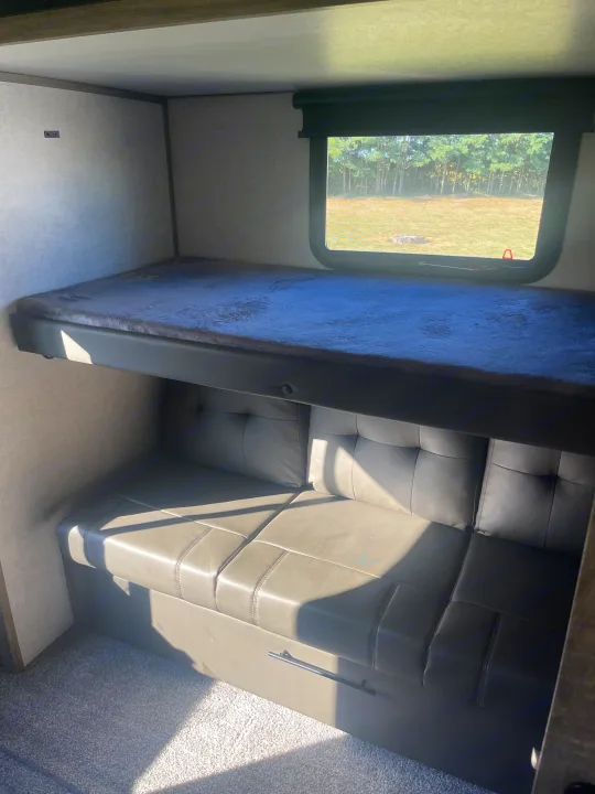 RV rental interior featuring comfortable bunk beds, a convertible sofa, and a window offering a scenic outdoor view.. Forest River Salem Hemisphere 2020
