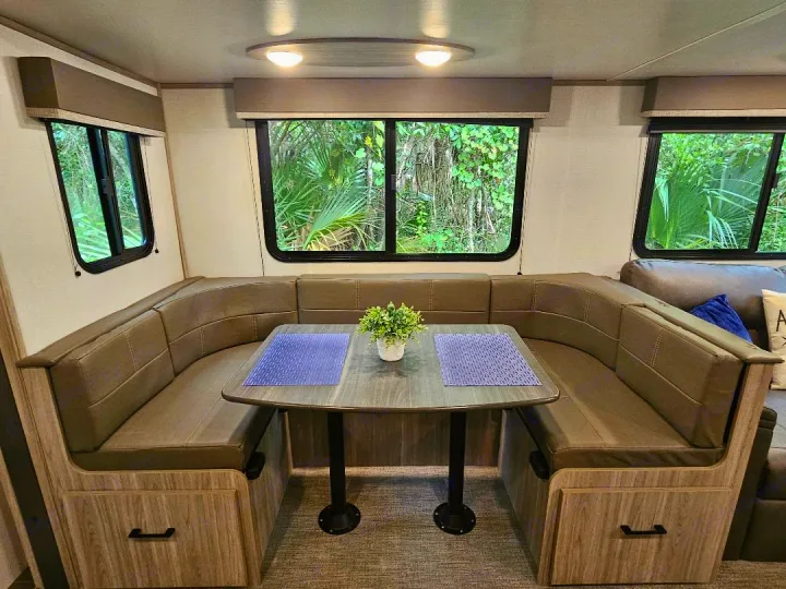 Spacious RV rental dinette featuring U-shaped seating, a table, and large windows. Perfect for dining & relaxing.. Keystone RV Passport SL 2021