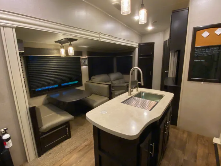 Experience comfort in this modern RV rental interior, featuring a kitchen island, dining booth, and cozy living area.. Jayco Eagle 2020