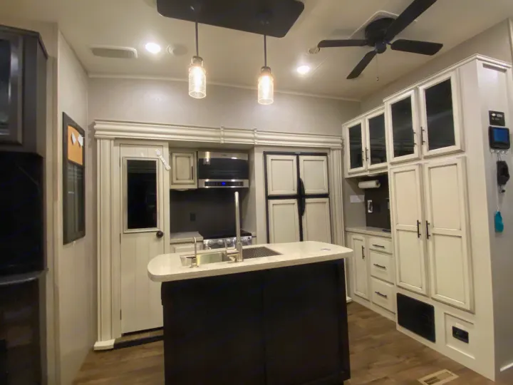 Modern RV rental kitchen interior with island sink, integrated appliances, and spacious white cabinetry.. Jayco Eagle 2020