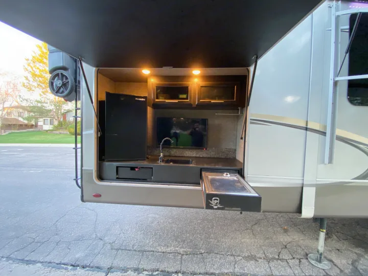 This RV rental's outdoor kitchen boasts a fridge, TV, sink, and pull-out grill for camping trips.. Jayco Eagle 2020