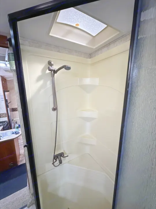 RV rental: Bright, clean shower stall with cream walls, built-in shelves, and skylight for natural light.. Keystone RV Montana High Country 2010