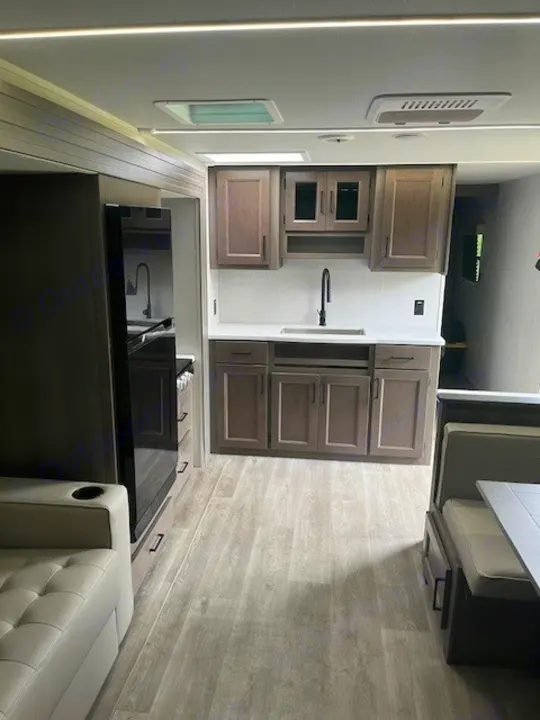 Modern rv rental interior with a light wood-look floor, well-equipped kitchen, and comfortable dining/living spaces.. Grand Design Transcend Xplor 2024