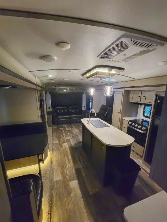 Spacious RV rental interior featuring a modern kitchen island, living area, and wood floors.. Keystone RV Outback 2019