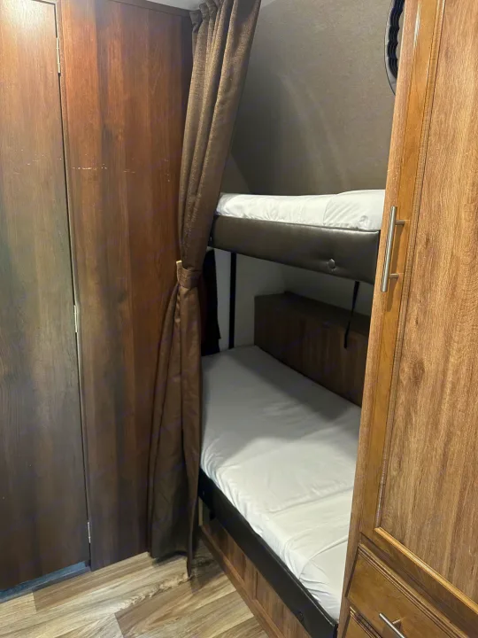 RV rental interior features comfortable bunk beds with white linens and built-in wood-grain storage cabinets.. Jayco Jay Flight 2018
